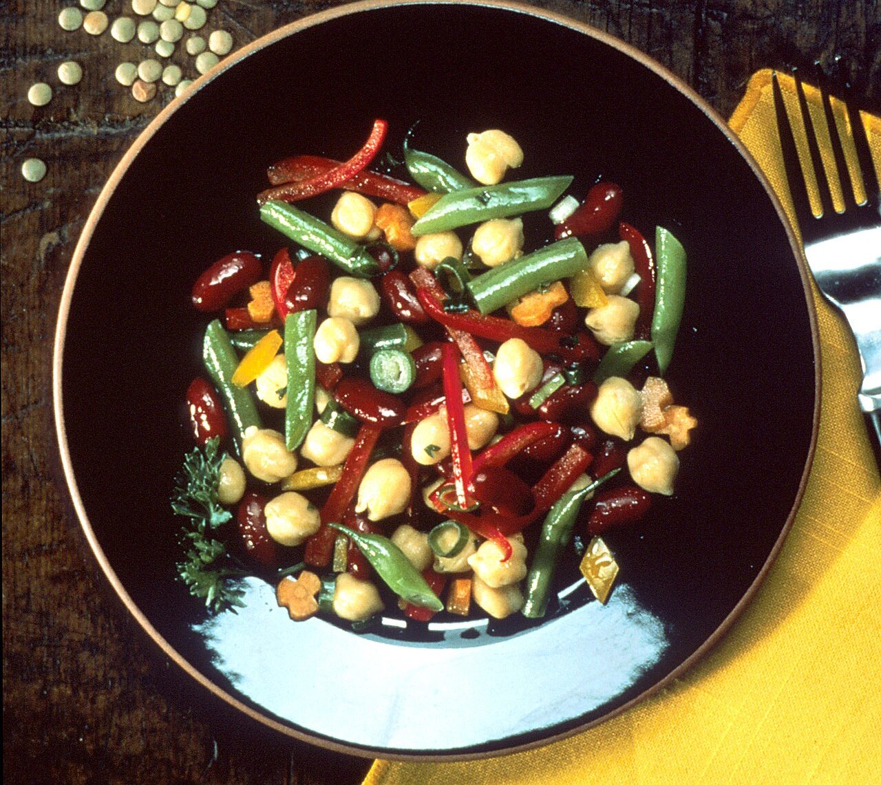Salade de haricots rouges, pois chiches et haricots verts dans une assiette noire